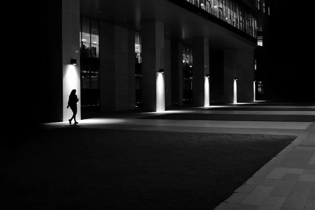 Silhouette of a lady walking in front of a building